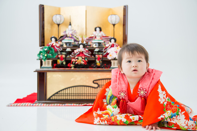 雛人形と一緒に写る祝着の女の子の写真